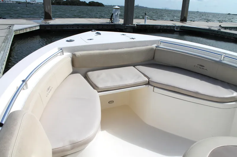 Slide: The Image of 2018 Cobia 220 Center Console boat with cushioned seating, docked by the water. - 21