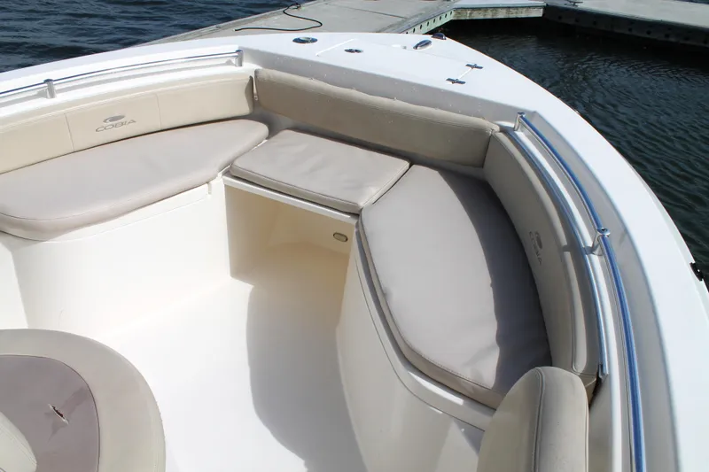 Slide: The Image of 2018 Cobia 220 Center Console boat with cushioned seating, docked by the water. - 22