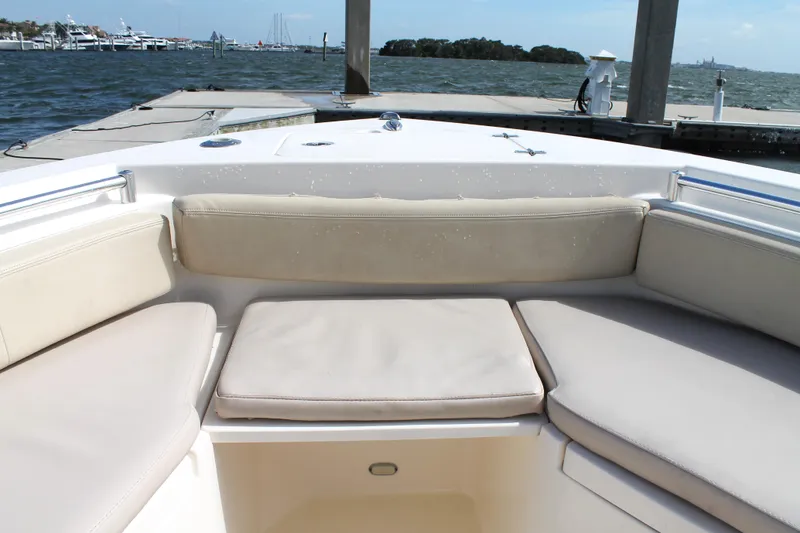 Slide: The Image of 2018 Cobia 220 Center Console boat with cushioned seating, docked by the water. - 23