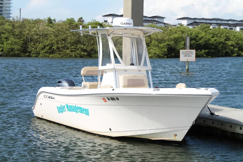 Slide: The Image of 2018 Cobia 220 Center Console boat docked on calm water. - 7