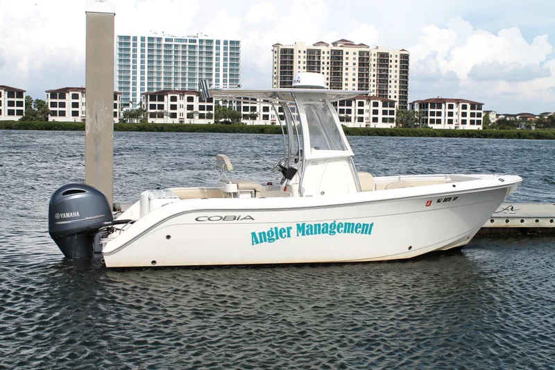 Slide: The Image of 2018 Cobia 220 Center Console boat docked on water with Yamaha engine. - 9