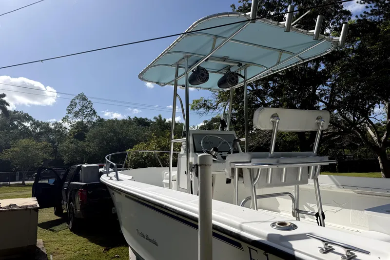 Slide: The Image of Edgewater 200CC 1999 boat with T-top and seating, parked outdoors on a sunny day. - 11