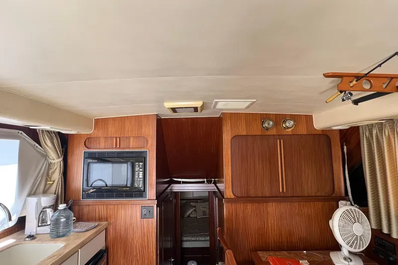 Slide: The Image of Interior of a 1990 Hatteras 41 Convertible yacht with wood paneling and kitchen amenities. - 16