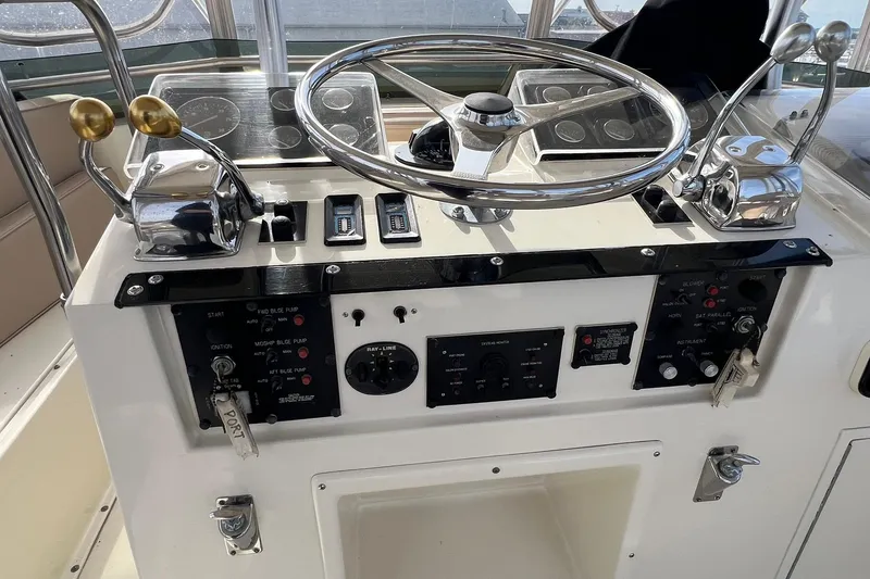 Slide: The Image of Control panel of a 1990 Hatteras 41 Convertible boat with steering wheel and throttle levers. - 6