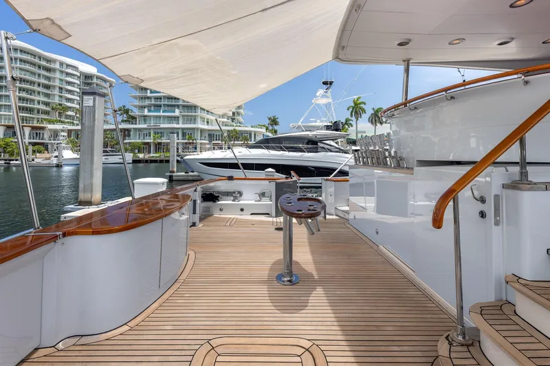 Slide: The Image of Luxurious 1998 Trinity Yachts deck with wooden flooring, docked near modern waterfront buildings. - 7
