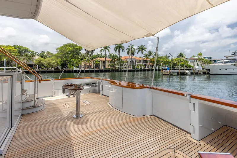 Slide: The Image of Luxurious 1998 Trinity Yachts deck with wooden flooring, overlooking serene waterfront and palm trees. - 9