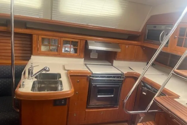 Slide: The Image of 2007 Hunter 45 Center Cockpit yacht kitchen with wooden cabinetry and modern appliances. - 12