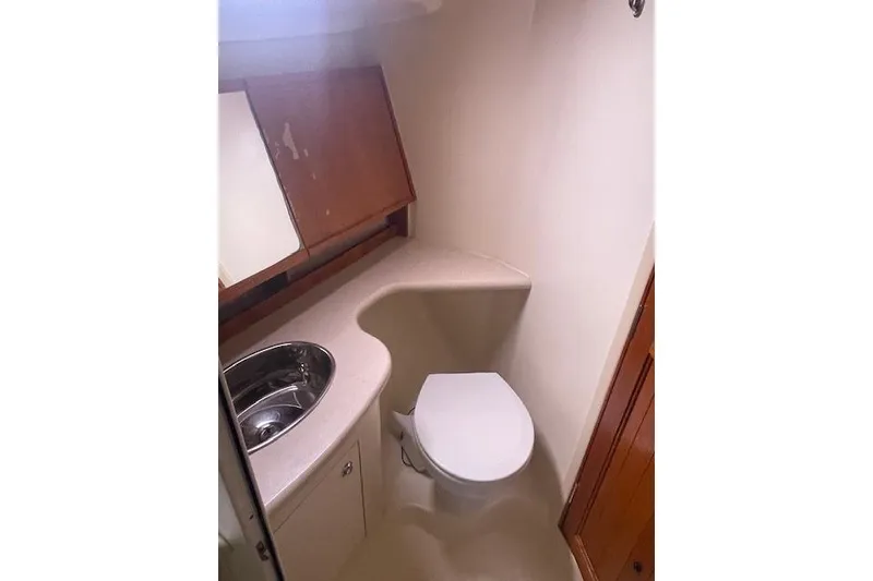 Slide: The Image of 2007 Hunter 45 Center Cockpit bathroom with sink, toilet, and wooden cabinetry. - 17