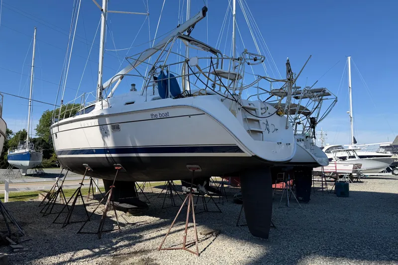 Slide: The Image of 2007 Hunter 45 Center Cockpit sailboat on stands in a boatyard under clear blue sky. - 2
