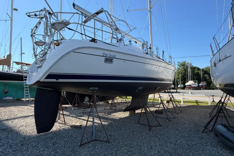 Slide: The Image of 2007 Hunter 45 Center Cockpit sailboat on stands in a boatyard under clear blue sky. - 3