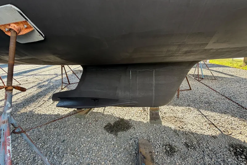 Slide: The Image of 2007 Hunter 45 Center Cockpit sailboat keel on gravel, supported by stands. - 4
