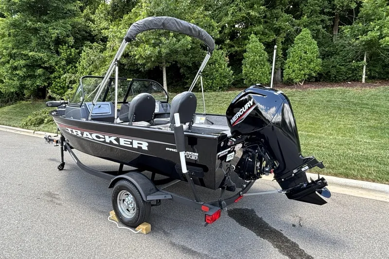 Slide: The Image of 2025 Tracker Pro Guide V-16 WT boat with Mercury engine on trailer, parked outdoors. - 12
