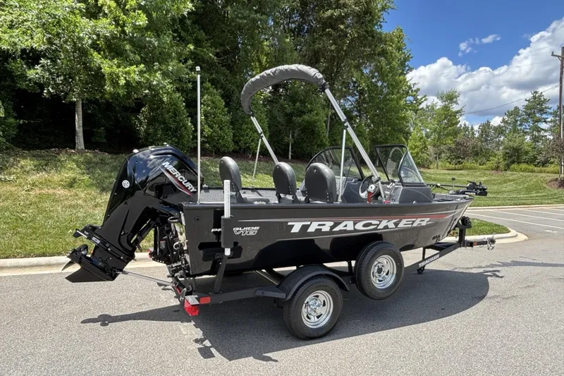 Slide: The Image of 2025 Tracker Pro Guide V-16 WT boat on trailer, parked outdoors, with Mercury outboard motor. - 4