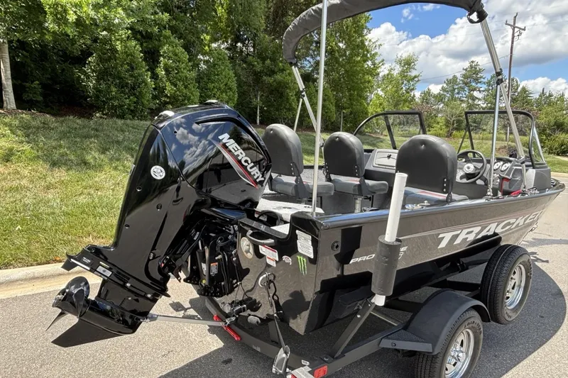 Slide: The Image of 2025 Tracker Pro Guide V-16 WT boat with Mercury engine on trailer, parked outdoors. - 5