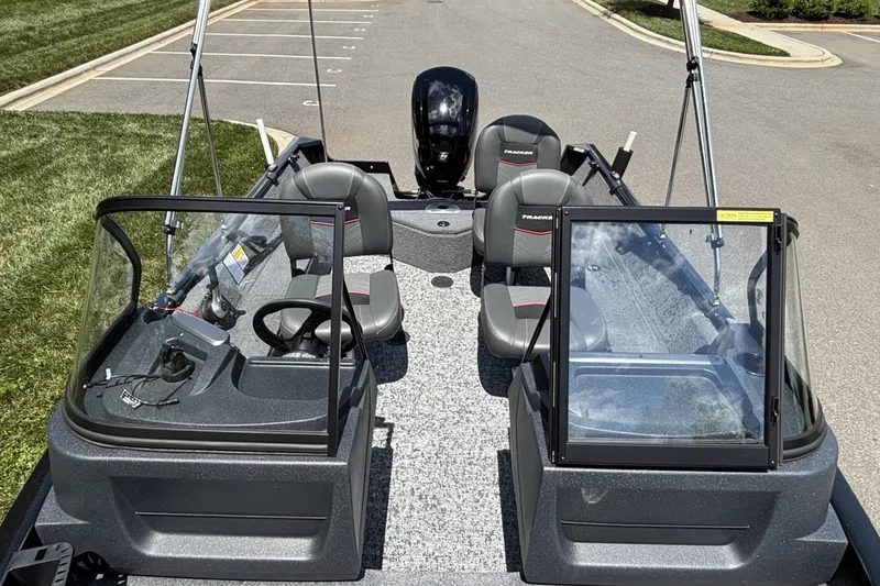 Slide: The Image of 2025 Tracker Pro Guide V-16 WT boat with seating and steering console, parked on pavement. - 8