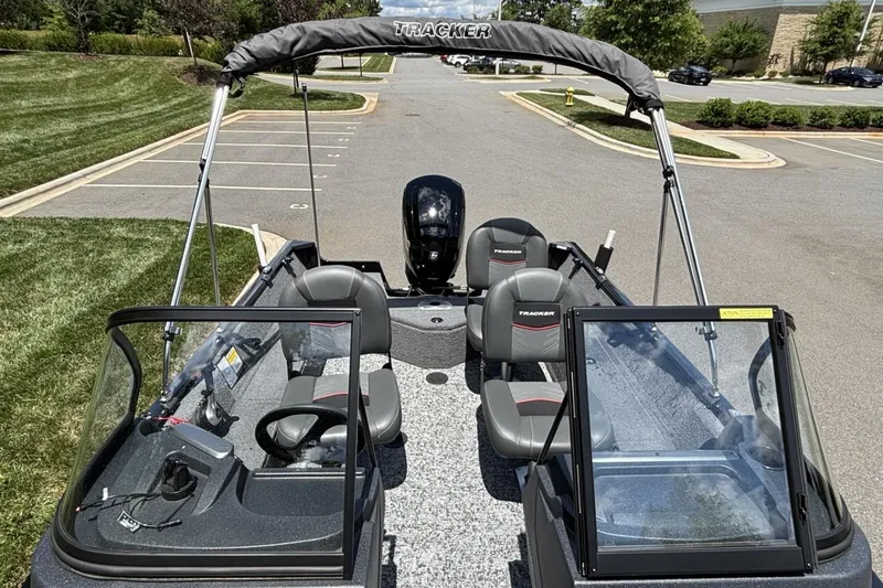 Slide: The Image of 2025 Tracker Pro Guide V-16 WT boat with seating and windshield, parked outdoors. - 9