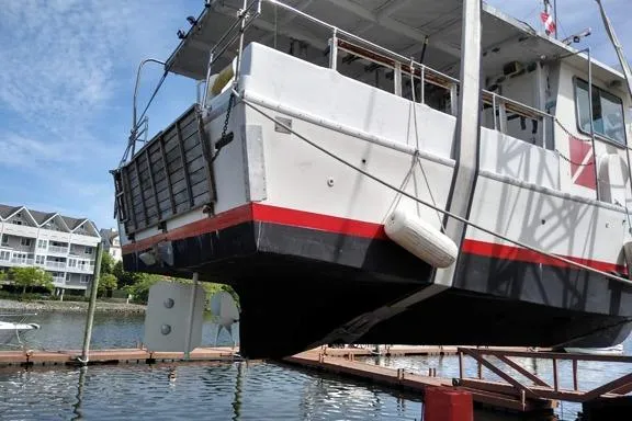 Slide: The Image of 1980 Thompson Passenger and Dive Trawler lifted at dockside, with waterfront buildings in background. - 12