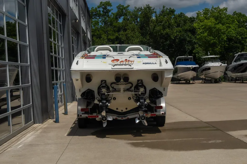 Slide: The Image of 2002 Formula 382 FASTech boat on trailer, parked outside a building with other boats nearby. - 4