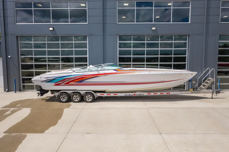 Slide: The Image of 2002 Formula 382 FASTech boat on trailer, vibrant graphics, parked outside modern building. - 6