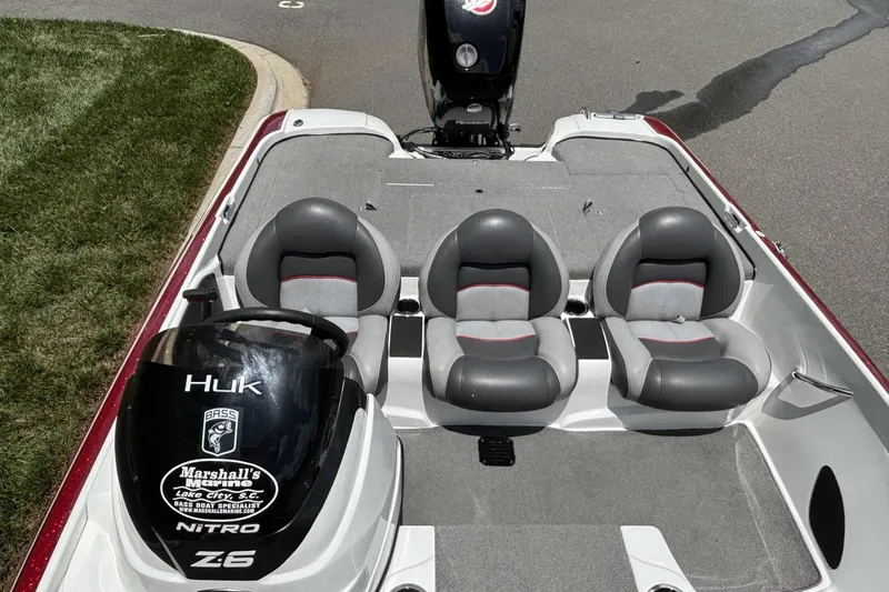 Slide: The Image of 2014 Nitro Z-6 boat interior with three gray seats and a motor, parked on pavement. - 9