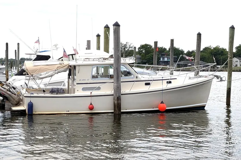 The Image of 2003 Atlas Acadia 32 boat docked at marina with buoys and flags. - 1