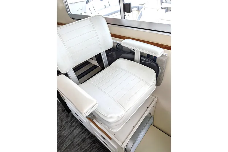 Slide: The Image of White captain's chair inside a 2003 Atlas Acadia 32 boat, near a window. - 18