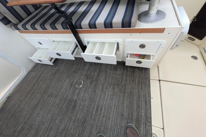 Slide: The Image of Interior of 2003 Atlas Acadia 32 boat with open storage drawers and striped seating. - 23