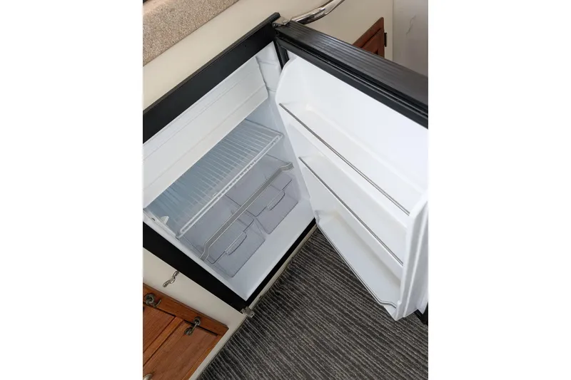 Slide: The Image of Open refrigerator inside 2003 Atlas Acadia 32, showing empty shelves and door compartments. - 32