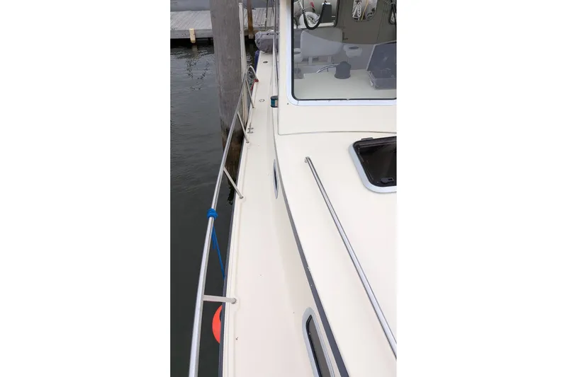Slide: The Image of Side view of 2003 Atlas Acadia 32 boat docked, showing deck and railing. - 41
