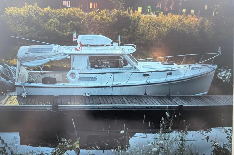 Slide: The Image of 2003 Atlas Acadia 32 boat docked by a serene riverside with lush greenery. - 47