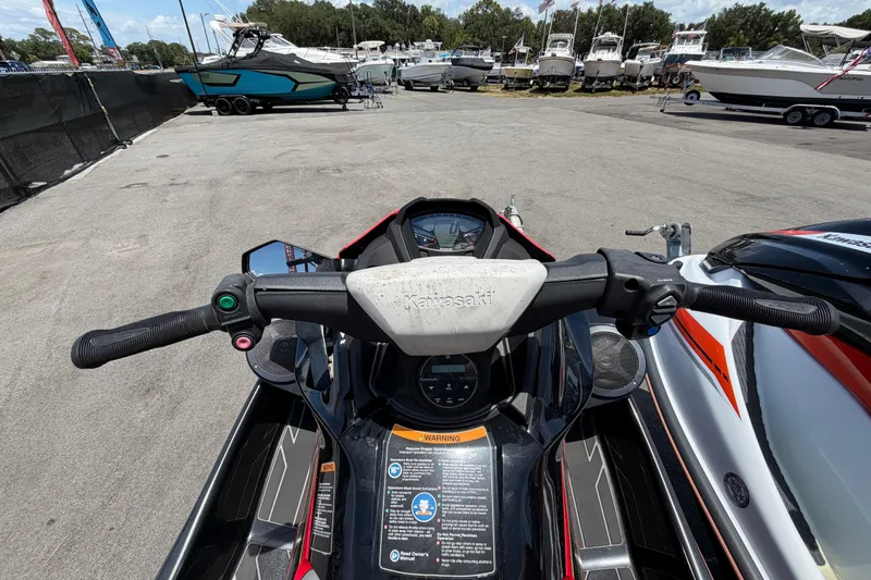 Slide: The Image of 2024 Kawasaki Jetski STX 160LX handlebars and dashboard view at a marina. - 12