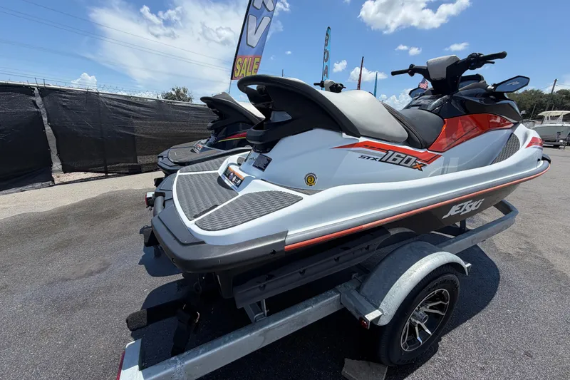 Slide: The Image of 2024 Kawasaki Jetski STX 160LX on trailer, displayed outdoors under a sunny sky. - 2
