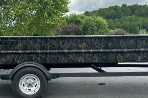 Slide: The Image of 2025 Tracker Grizzly 1860 AWL boat on trailer, camo design, parked outdoors. - 12
