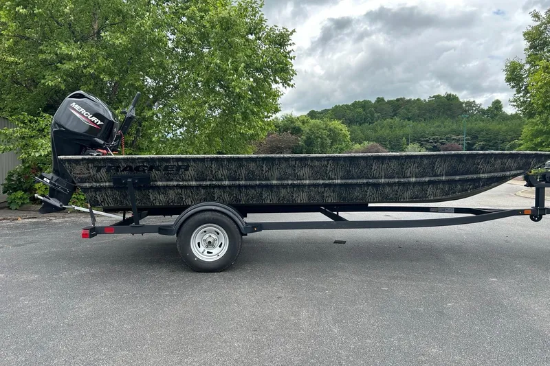 The Image of 2025 Tracker Grizzly 1860 AWL boat on trailer, parked outdoors with trees in background. - 1