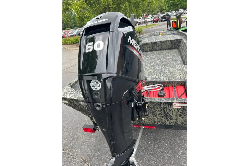 Slide: The Image of 2025 Tracker Grizzly 1860 AWL boat with Mercury 60 outboard motor, parked outdoors. - 4