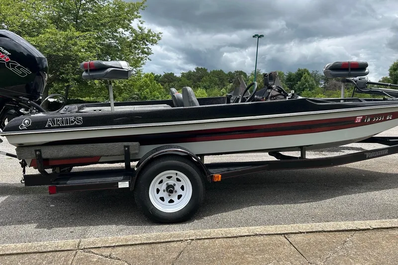 Slide: The Image of 1988 Aries Bass boat on trailer, parked outdoors under cloudy sky. - 2