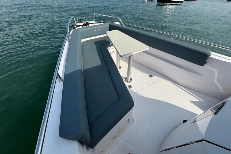 Slide: The Image of 2022 Axopar 28 Cabin boat with spacious seating and table on calm water. - 12