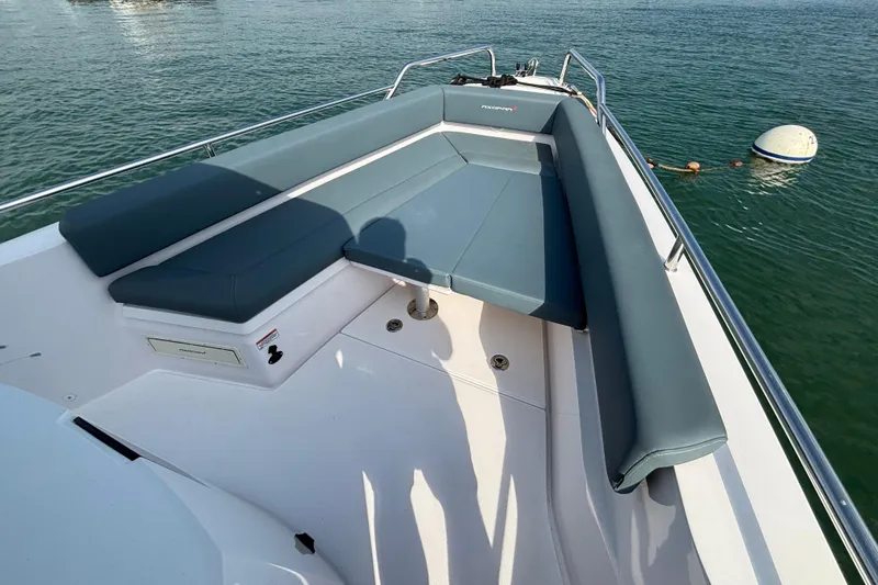 Slide: The Image of 2022 Axopar 28 Cabin boat with cushioned seating on calm water. - 14