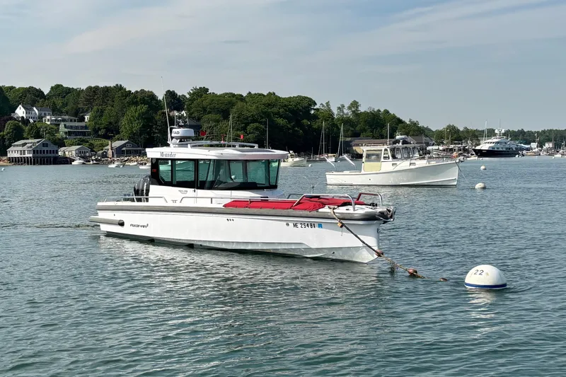 Slide: The Image of 2022 Axopar 28 Cabin boat moored in a scenic harbor setting. - 2