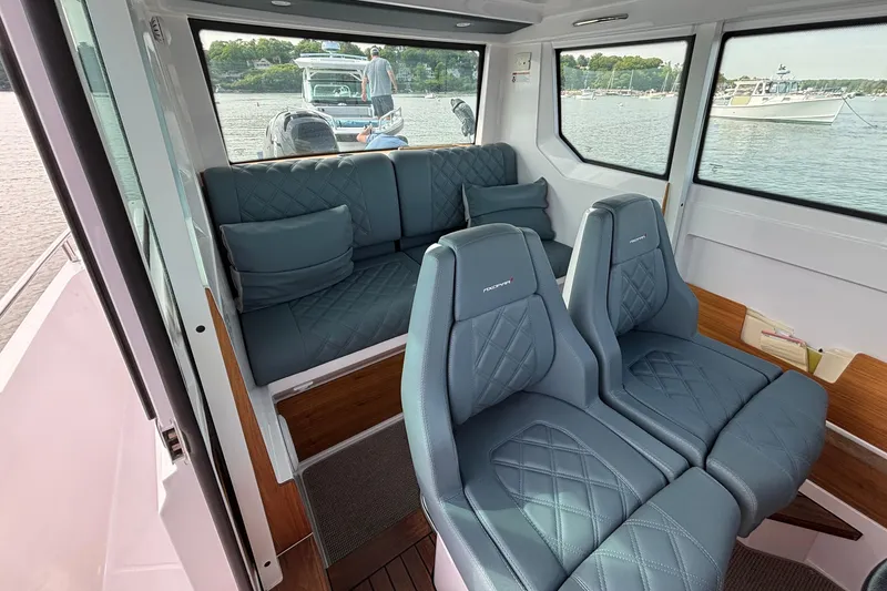 Slide: The Image of Interior of 2022 Axopar 28 Cabin boat with blue quilted seating and scenic water view. - 21