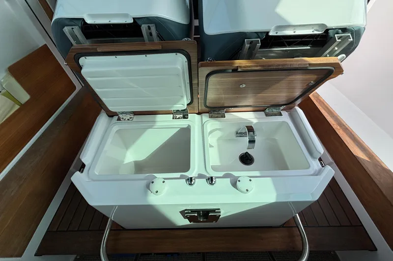 Slide: The Image of 2022 Axopar 28 Cabin boat interior with open storage compartments and sink. - 22