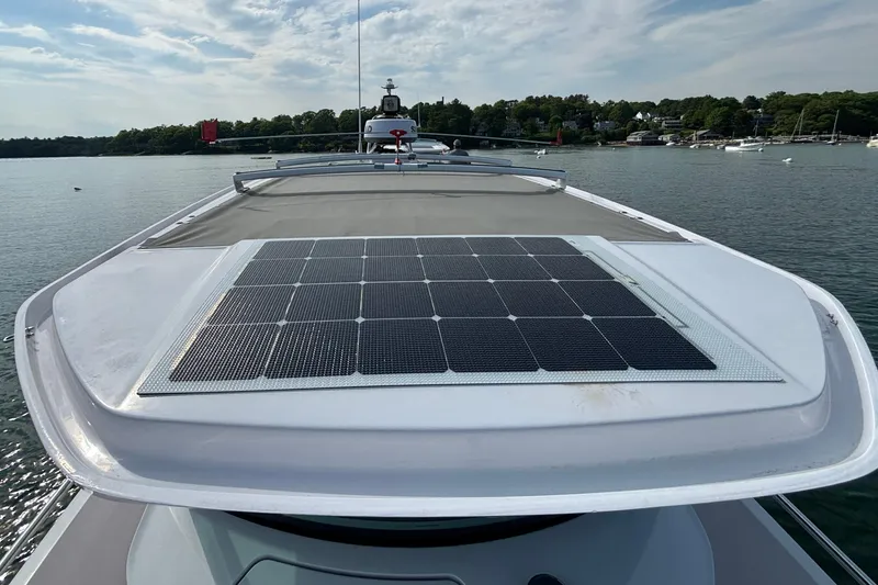 Slide: The Image of 2022 Axopar 28 Cabin boat with solar panels on the roof, docked on a calm lake. - 25