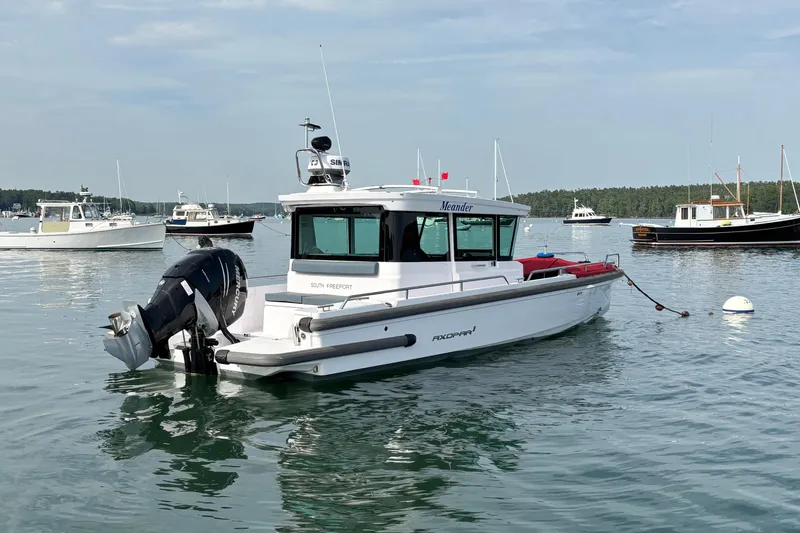 Slide: The Image of 2022 Axopar 28 Cabin boat moored in a scenic harbor with other vessels. - 3