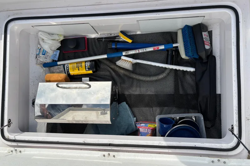Slide: The Image of Storage compartment of 2022 Axopar 28 Cabin boat with cleaning supplies and tools. - 36