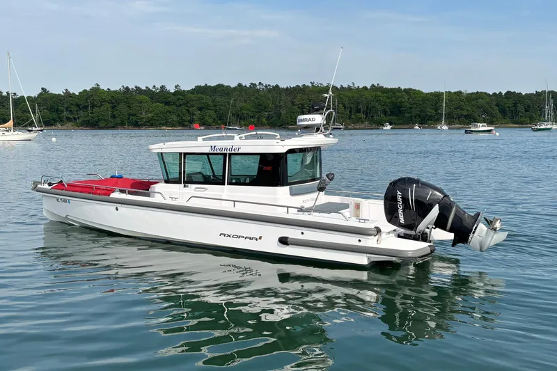Slide: The Image of 2022 Axopar 28 Cabin boat on calm water with scenic background. - 5