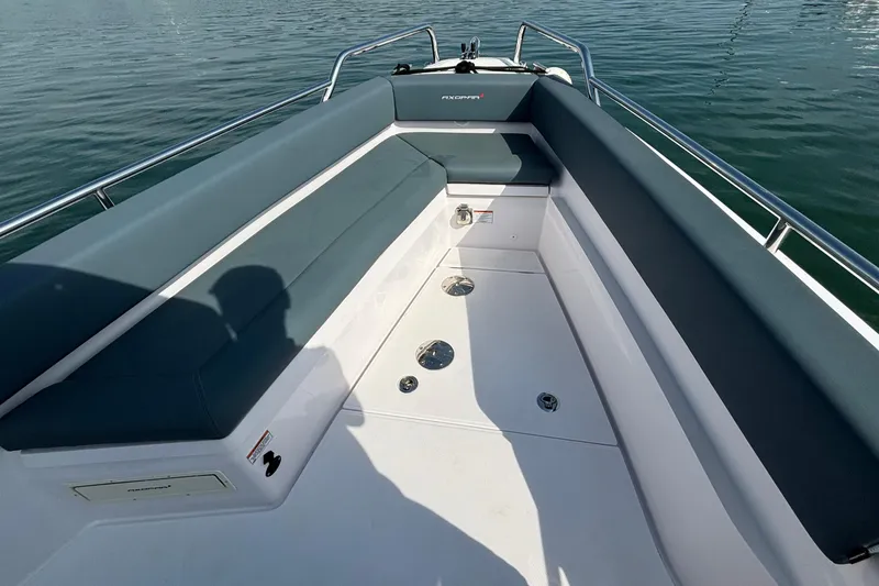Slide: The Image of 2022 Axopar 28 Cabin boat interior with cushioned seating and sleek design on calm water. - 8