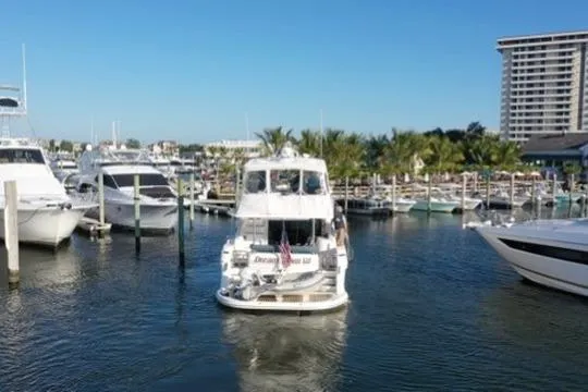 Slide: The Image of 2005 Neptunus 56 Flybridge yacht navigating marina with palm trees and high-rise building. - 16