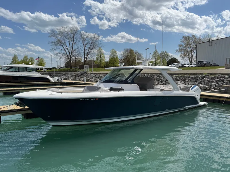 The Image of Tiara Yachts 38 LS 2024 docked in a marina, surrounded by clear water and cloudy sky. - 0