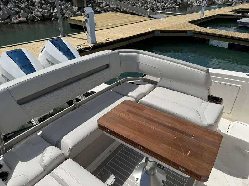 Slide: The Image of 2024 Tiara Yachts 38 LS with elegant seating area and wooden table by the water. - 10