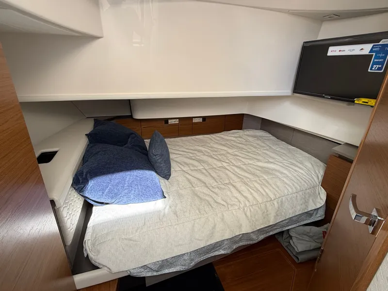 Slide: The Image of Cabin with a double bed, blue bedding, and a wall-mounted TV. - 37